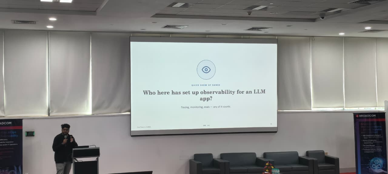 Varun speaking at a podium next to a slide asking who has set up observability for an LLM app